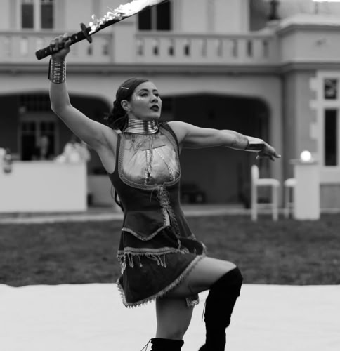 A person performing with a flaming sword in front of a large building.